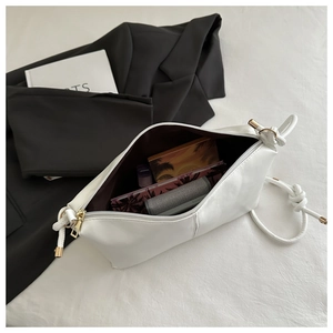 Close-up of minimalist white PU leather crossbody bag showing golden zipper and knotted strap