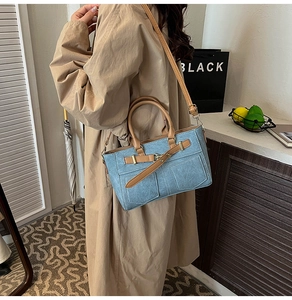 Dettaglio di borsa tote in denim blu e pelle marrone indossata da una modella con trench coat