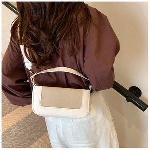 Vista esterna di una borsa a spalla minimalista in bianco e beige indossata da una modella