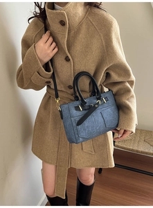 Borsa blu in denim con finiture dorate indossata su un cappotto di lana lungo