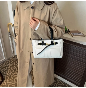 Dettaglio della borsa bicolore minimalista con cinturino decorativo e finiture dorate