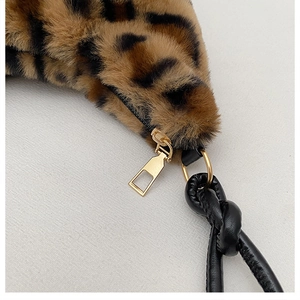 Detail of leopard print faux fur texture with gold zipper and black woven handle