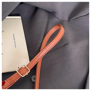 Detail of orange brown PU leather shoulder strap with gold metal adjustment buckle