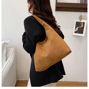 Side view of a large camel suede tote bag worn over the shoulder for a commuter look
