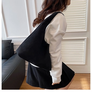 Minimalist black canvas crescent tote bag worn by a model in a modern interior setting