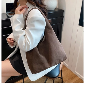 Deep brown suede tote bag worn on shoulder in a minimalist office setting