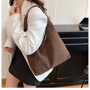 Detail of a large brown suede tote bag with a seamless wide strap for daily commute