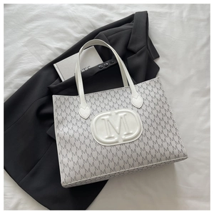 Macro detail of white faux leather tote bag with embossed M logo and letter print