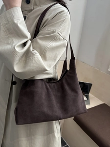 Brown suede crossbody bag with long strap, styled with a beige trench coat for daily commute