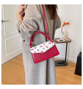 Detail of red and white cherry print handbag with knotted handle and shoulder strap