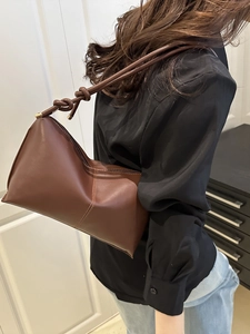 Brown leather tote bag with knotted shoulder strap and gold cylinder metal accents