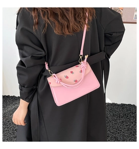 Detail of pink PU leather crossbody bag with red strawberry print and knotted handle