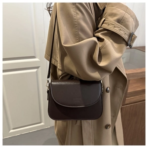 Model wearing dark brown minimalist crossbody bag with engraved logo and matte finish