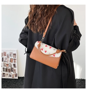 Lifestyle shot showing a brown and white printed small square bag with cherry heart patterns