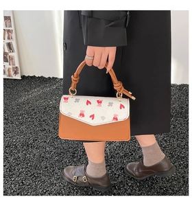 Detail of color-block handbag featuring a bear print flap and twisted leather handle