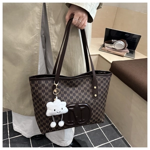Gros plan du sac cabas marron avec motif M et accessoire charm en forme de nuage blanc