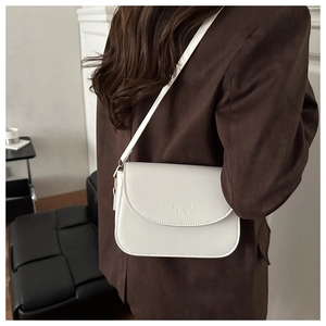 Detailed view of white leather square bag with 'FASHION BAGS' text worn by model
