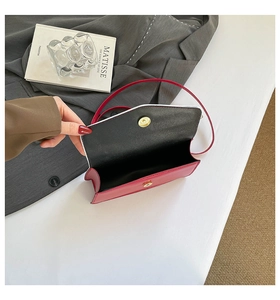 Detailed top view of red leather envelope bag with gold magnetic snap and black lining