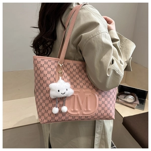 Detailed view of pink tote bag with letter M print and white cloud plush charm