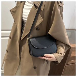 Classic black leather crossbody bag styled with a khaki trench coat for a chic look
