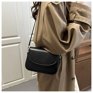 Detail shot of the black matte leather crossbody bag showing its elegant square flap design