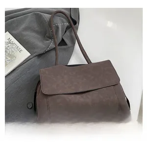 Detail of dark coffee matte handbag featuring a flap closure and long shoulder strap