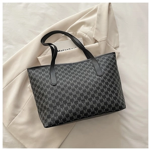 Détail du sac cabas matelassé avec monogramme M et poignées en cuir noir élégantes