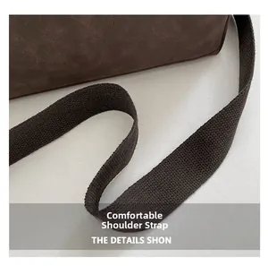 Detail of a dark brown suede tote bag with a matching wide woven comfortable shoulder strap