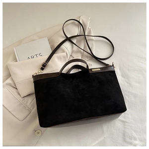 Close-up of retro black suede and brown leather tote bag with elegant gold metal logo
