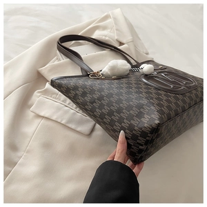 Détail du sac cabas marron foncé avec imprimé à motifs M et emblème de logo en cuir