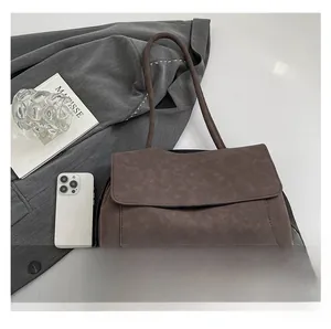 Detail view of brown faux leather crossbody bag with visible stitching and long strap