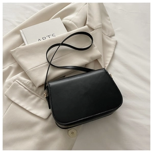Detail shot of the minimalist black leather crossbody bag with a sleek flap closure