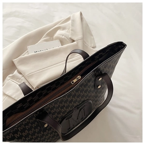 Détail du sac cabas à motif M avec poignées en cuir et rivets métalliques dorés