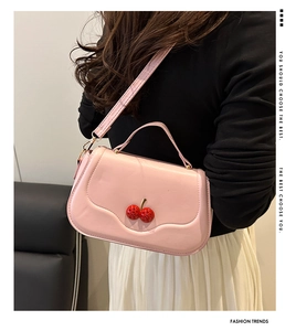 Pink cherry crossbody bag styled with a black top and white pleated skirt outfit