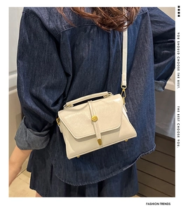Close-up of a cream white PU leather crossbody bag with golden buckle on a model