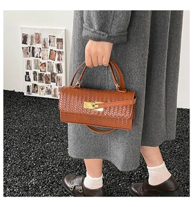 Close-up of brown woven texture handbag featuring a golden twist lock and dual handles
