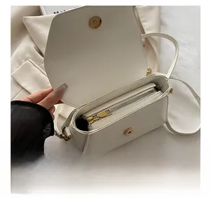 Detailoverzicht van de kleine witte leren tas met gladde metalen rits en binnenkant van de tas