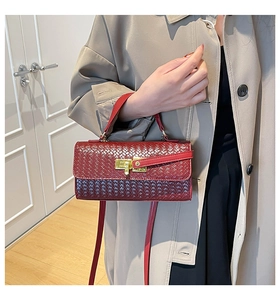 Détails d'un sac bandoulière tressé rouge foncé avec fermoir doré et poignée élégante