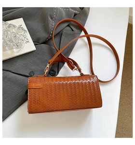 Détail de la texture en cuir tressé marron et des finitions dorées du sac Kelly