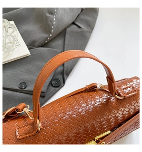 Détail du sac cylindre en cuir tressé marron avec finitions en métal doré poli