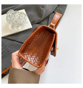 Détail du cuir tressé marron et du fermoir rotatif en métal doré sur le sac à main