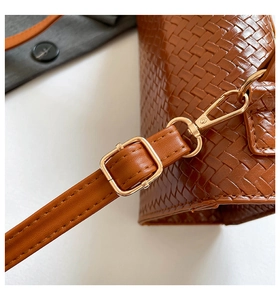 Détail de la texture tressée marron et du fermoir en métal doré sur le sac à bandoulière