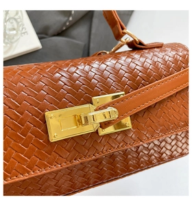 Vue macro de la texture en cuir tressé marron avec fermoir en métal doré rectangulaire