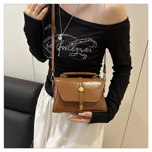 Detail van vintage bruine handtas met gouden gesp en stijlvolle schouderband