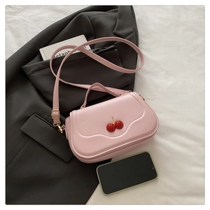 Detailed view of pink PU leather bag featuring cute cherry ornaments and gold metal hardware