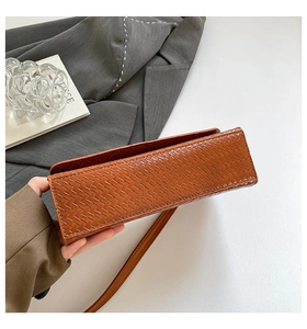 Détail de la texture tissée marron sur un sac à bandoulière rectangulaire minimaliste