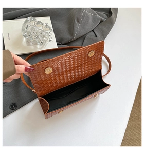 Détail de la texture cuir tressé marron sur le sac à rabat avec fermoir magnétique