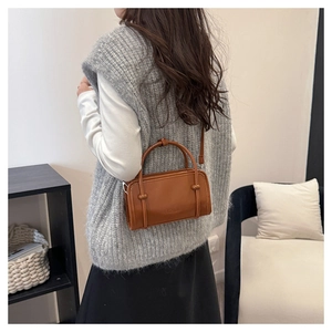 Brown leather crossbody bag with FASHION logo worn by model in a minimalist setting