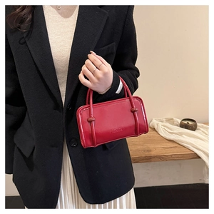 Detail of red leather handbag with FASHION embossing and unique knot strap design