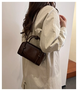 Model wearing dark brown vintage baguette bag with knot details on white background
